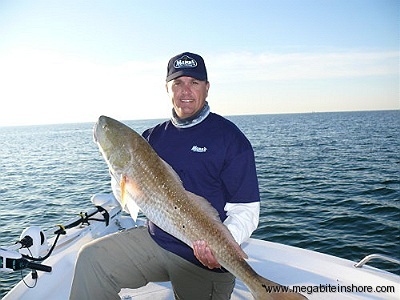 Capt. John with a big redfish. This big red hit a Mann's Tide Waker in 18ft of water right off Pensacola Beach