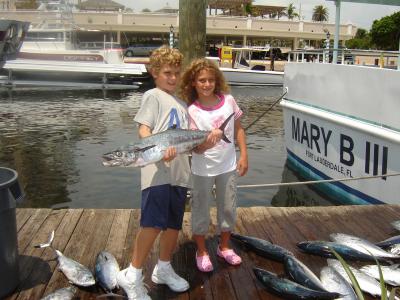 Cute brother and sister holding up the fish they caught
